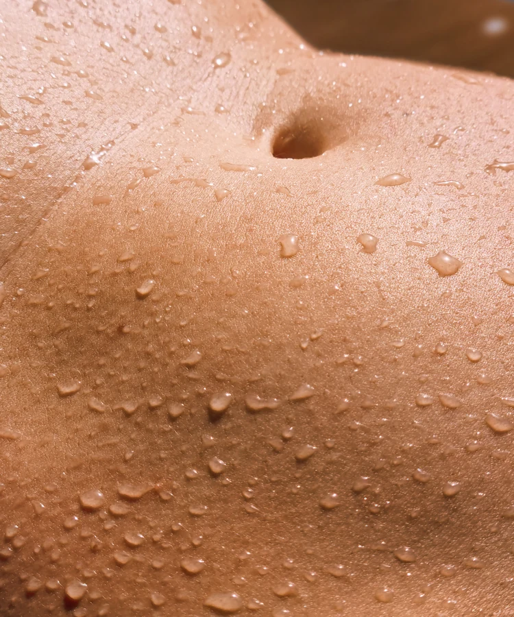 Woman's healthy glowing skin with water droplets after exercise or spa treatment