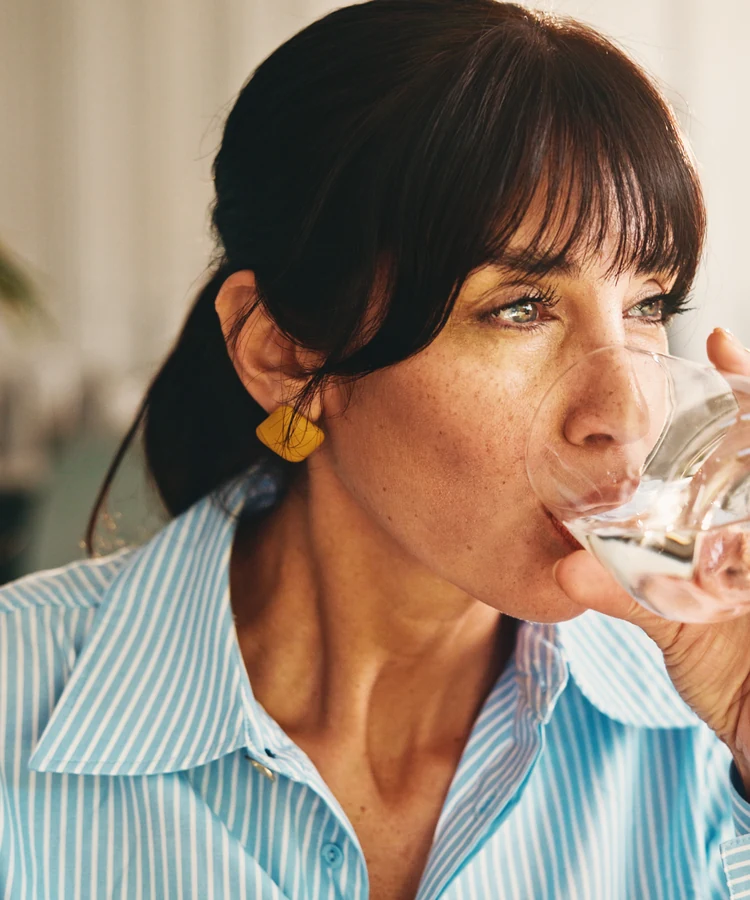 Woman drinking water from glass promoting healthy hydration habits for wellness and weight management