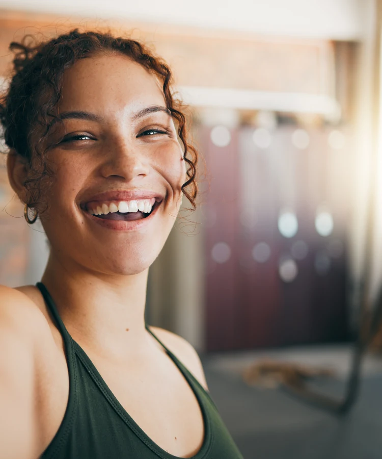 Happy woman in green athletic wear taking selfie after workout in fitness gym