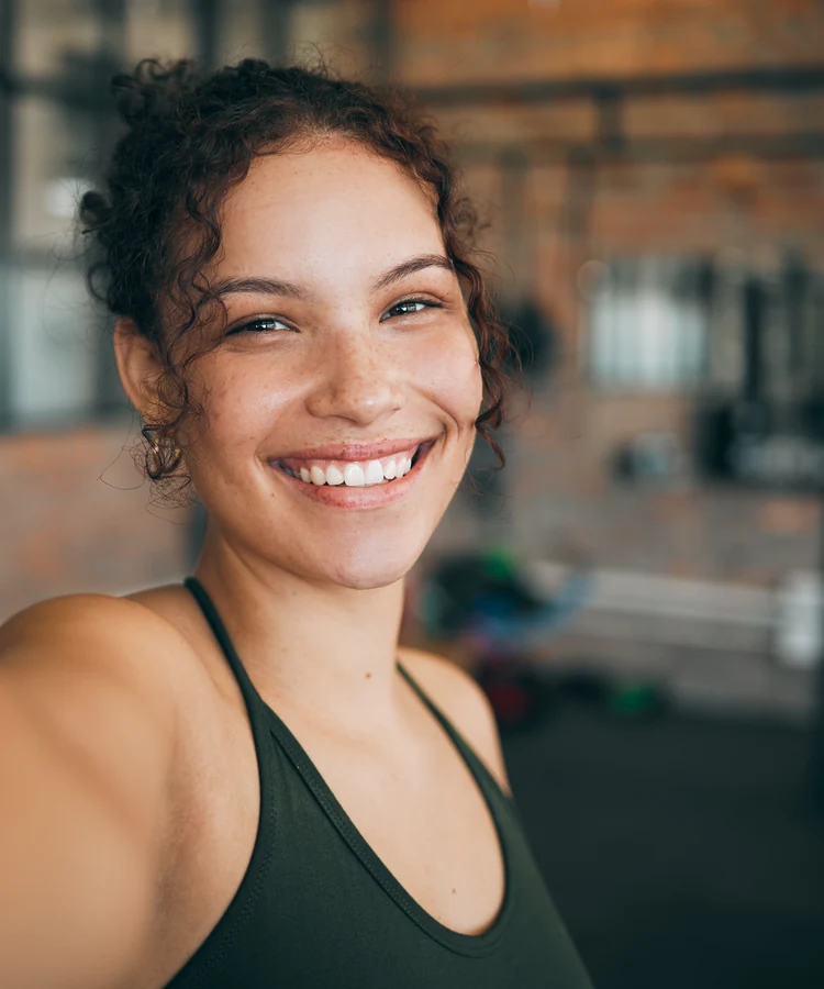 Happy woman in athletic wear taking selfie at gym smiling confidently after workout