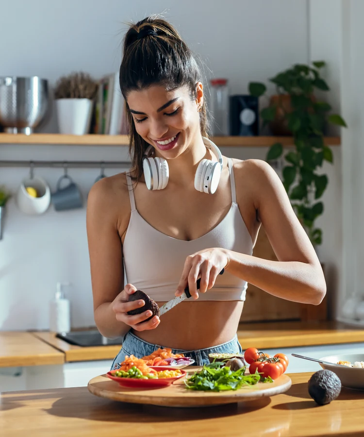 Woman in workout clothes preparing healthy vegetables in modern kitchen for weight loss nutrition