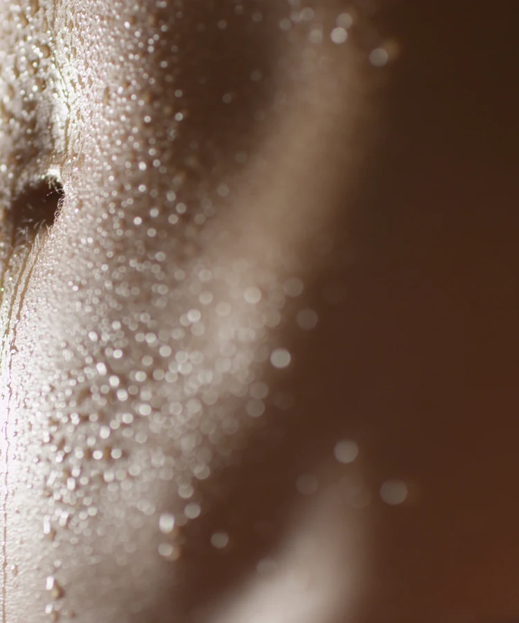 Woman with hydrated glowing skin covered in water droplets showcasing skincare and anti-aging wellness benefits