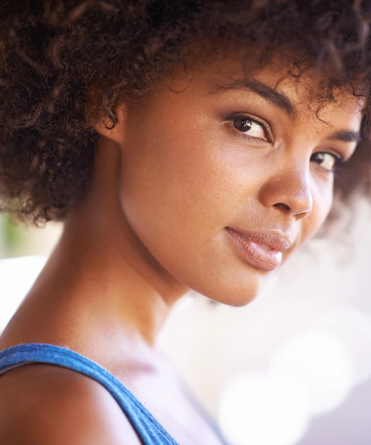 Confident young woman with natural curly hair and glowing skin representing health and wellness